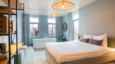 Overzicht van de Suite in Hotel Marktstad met tweepersoons king size bed, industrial kast met flatscreen televisie en vrijstaand bad