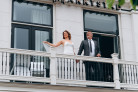 Net getrouwd stel geniet van uitzicht vanaf het balkon aan de voorzijde van Hotel Marktstad